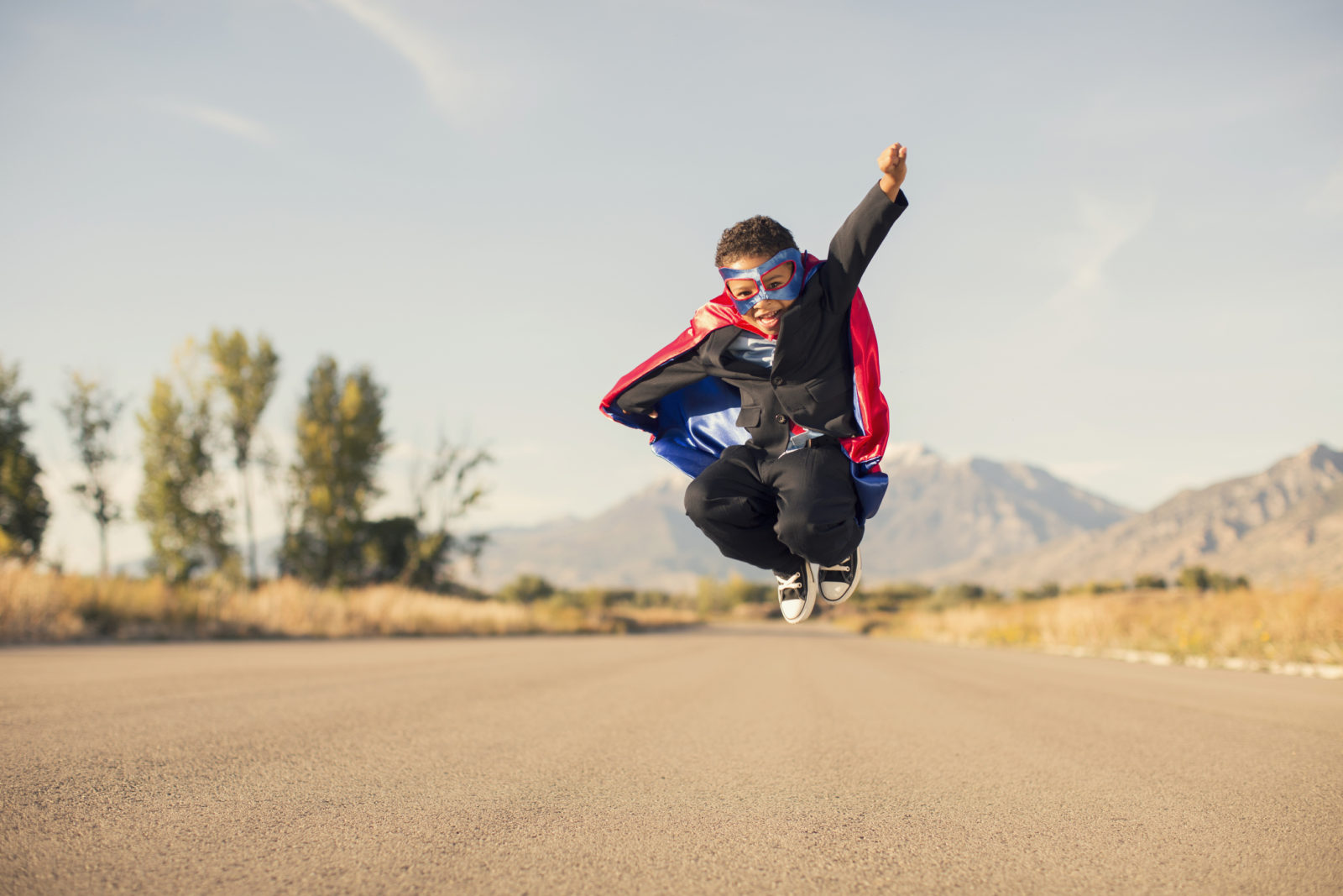 Boy Wearing Superhero Costume and Business Suit is Jumping | frustration-free compliance client engagements