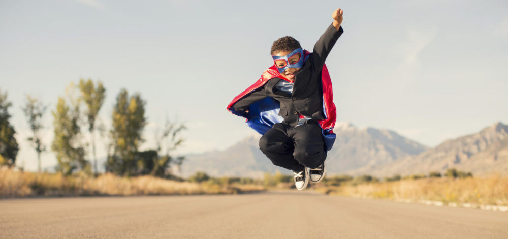 Boy Wearing Superhero Costume and Business Suit is Jumping | frustration-free compliance client engagements