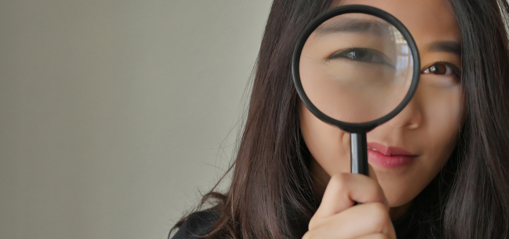 woman looking through magnifying glass | TCT Portal ROI calculator for compliance management