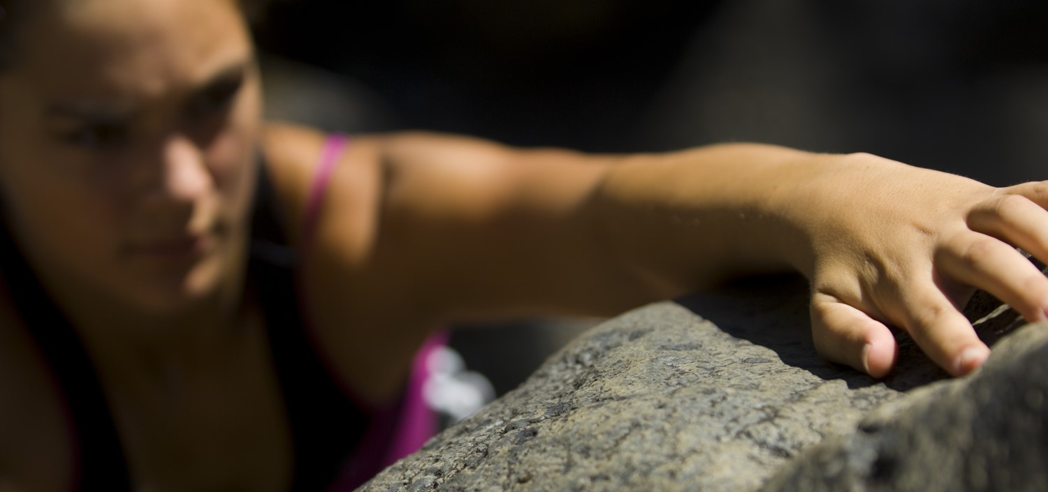 woman rock climber grabs a fingerhold | get a handle on HIPAA compliance