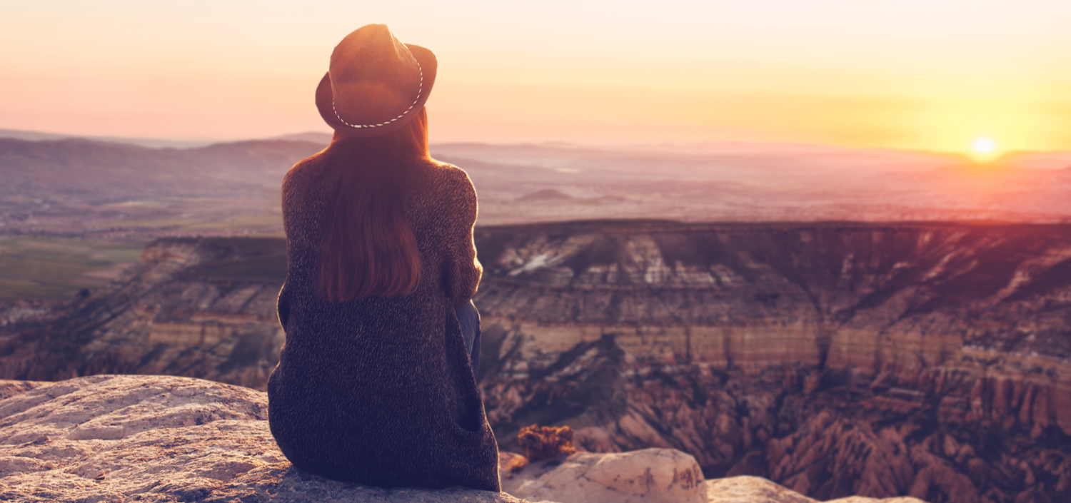 woman sitting on a mountain watching the sunrise | 2020 retrospective and doing business in 2021