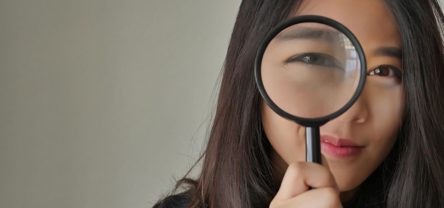 Woman looking through a magnifying glass and smiling | easy to provide evidence for compliance