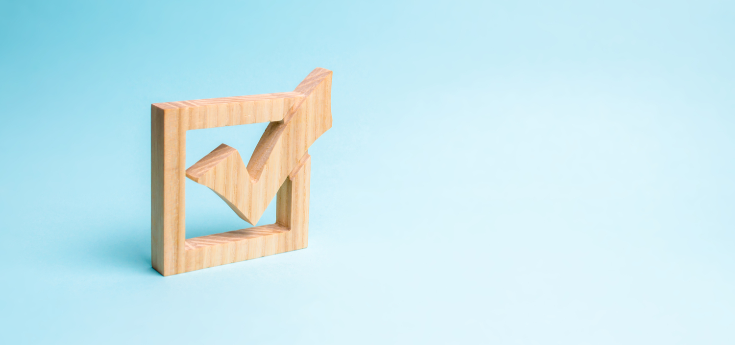 wooden checkmark on a blue background | questions to ask before buying compliance management software