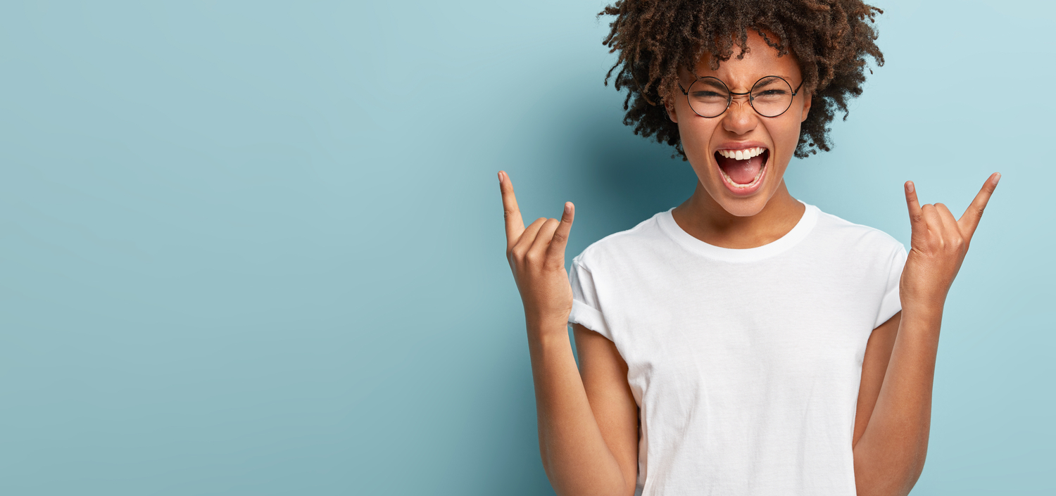 Young woman making rock ‘n’ roll sign against blue background | Tired of Compliance Chaos? Get Your Sh*t Together for PCI DSS 4.0