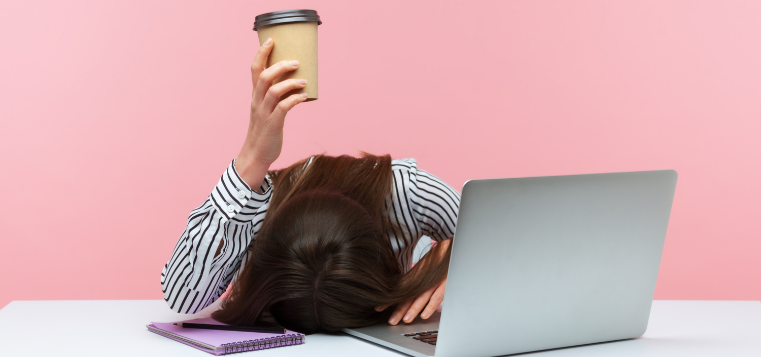 sleepy bored woman at her laptop holding a cup of coffee | Assessor's system making your company less efficient