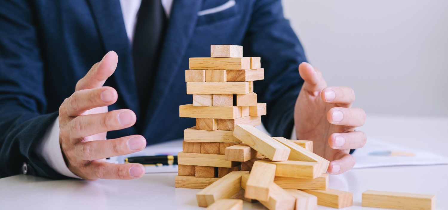 businessman with stack of wooden blocks falling | mistakes new compliance managers make