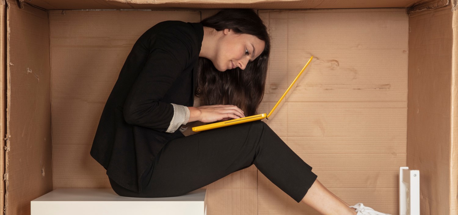 woman working on her laptop in a cramped box | customizable compliance management tool
