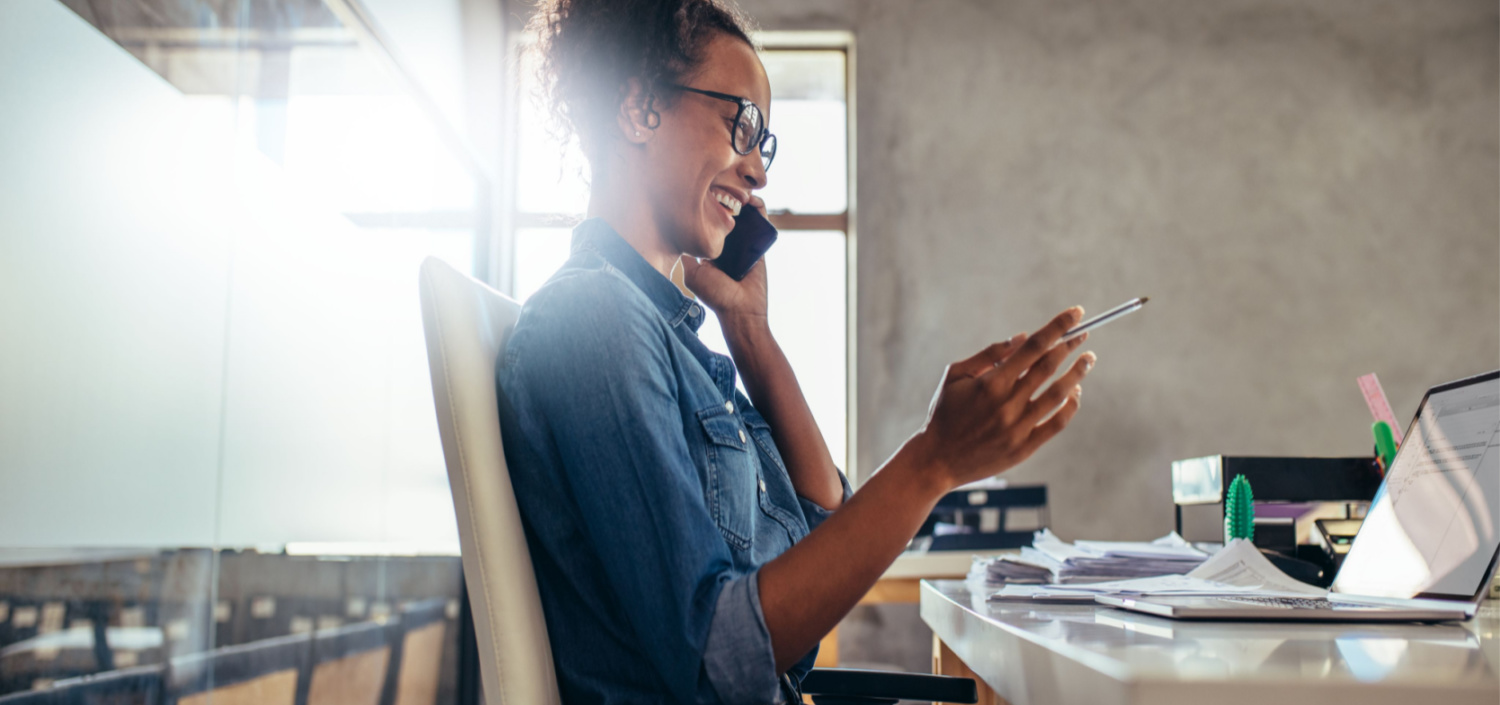 Smiling young businesswoman talking on phone with a laptop | TCT Portal service provider templates