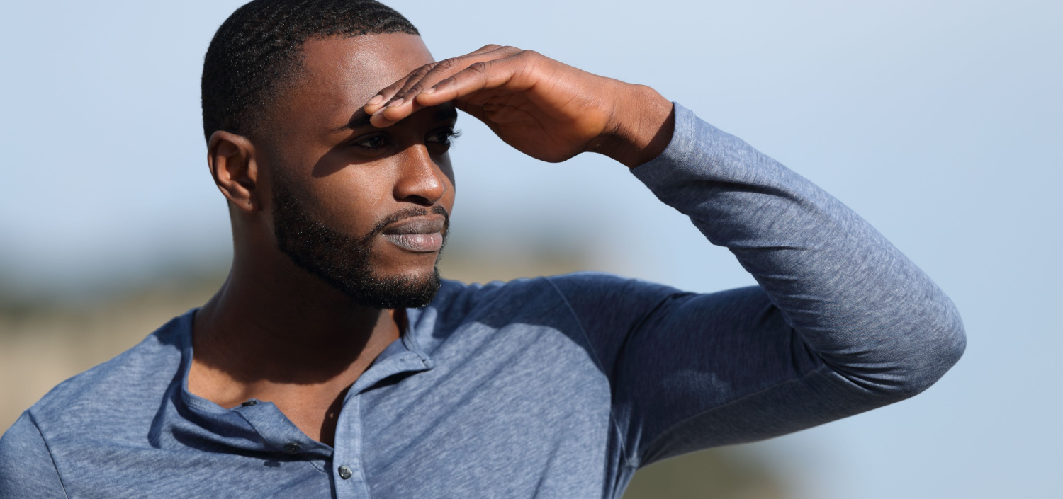 man looking into the distance and shading his eyes with his hand | security breach notifications in 2023