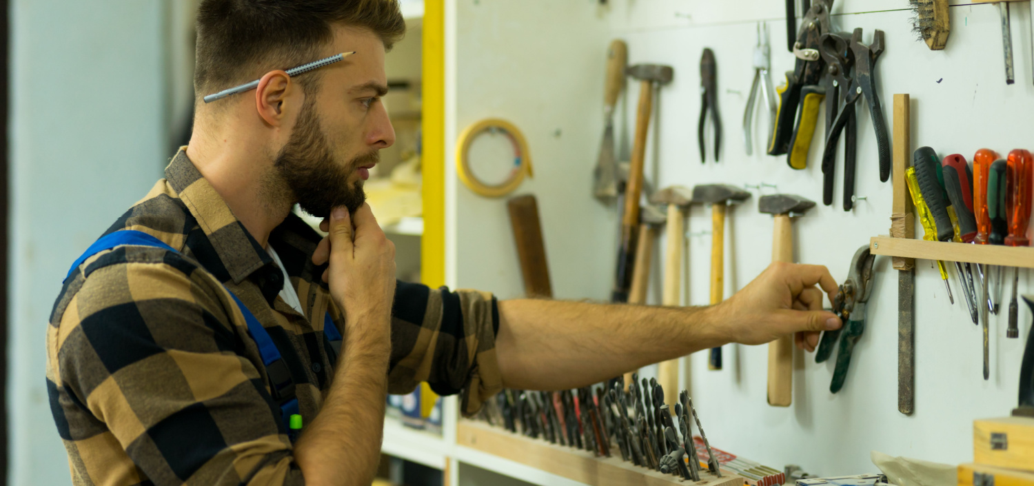 man selecting one of many tools that are hanging on a wall | one tool for multiple certifications