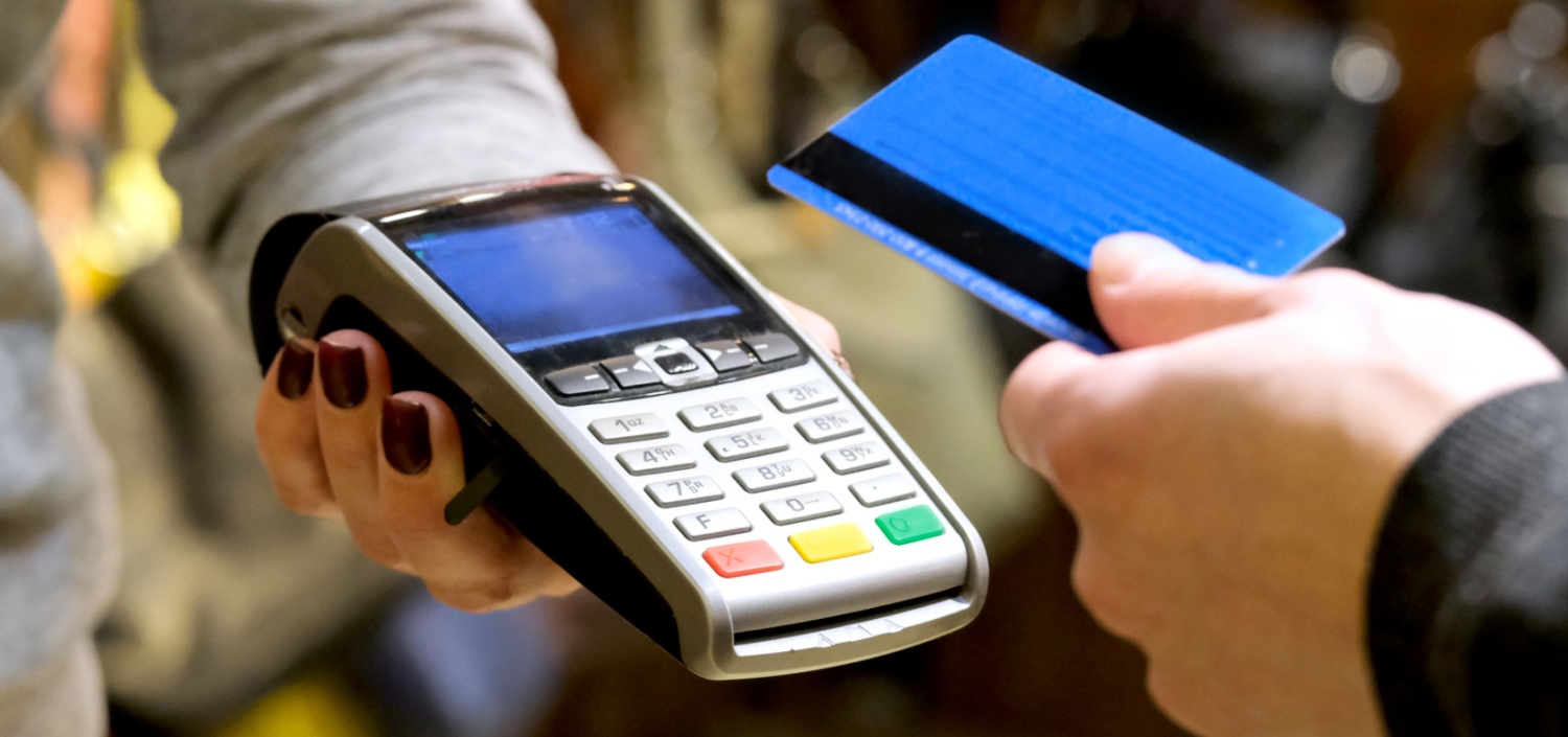 closeup of a card reader at a point of sale | Make PCI-DSS Easier for Retail and Restaurant Corporations