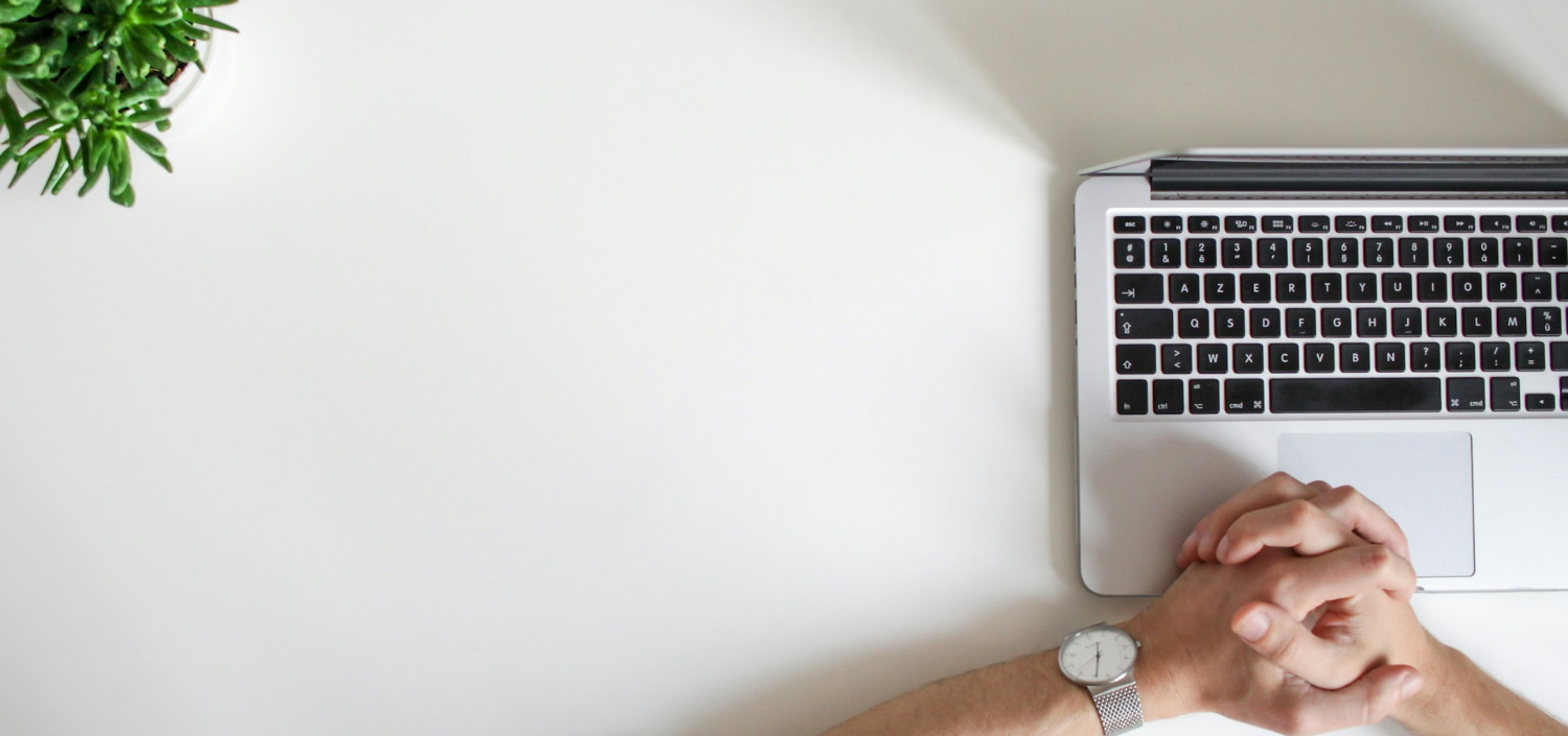 aerial view of hands clasped on desk with laptop | what to expect from PCI DSS 4.0.1